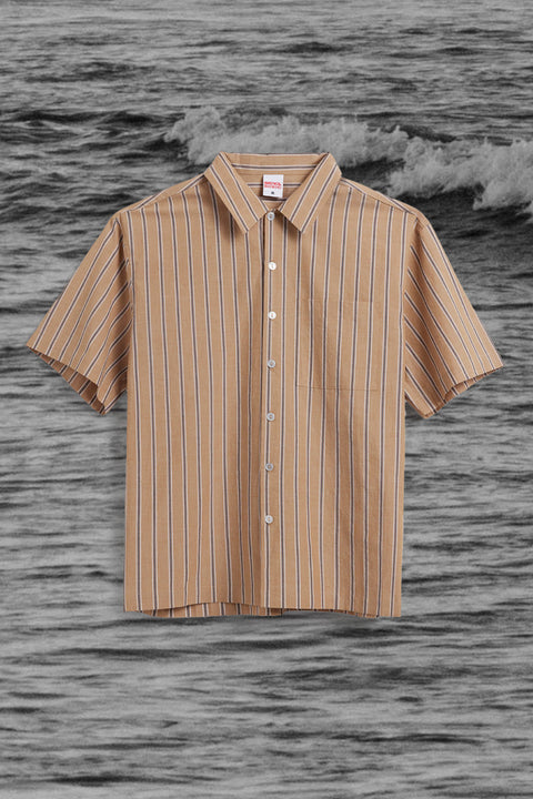 Tan button up short with vertical stripes over black and white ocean background.