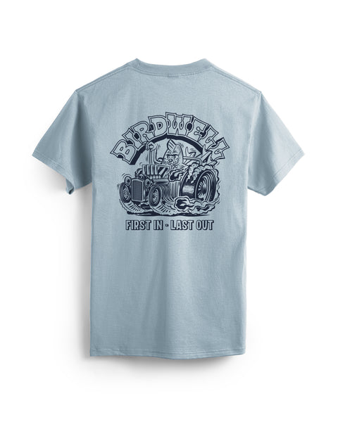 Back view of light blue t-shirt with screen printed graphic in navy on the back of shirt. Screen print depicts Birdie in a vintage race car with large back wheels with smoke coming out. Birdwell is written above in an outlined Slab Serif font. 