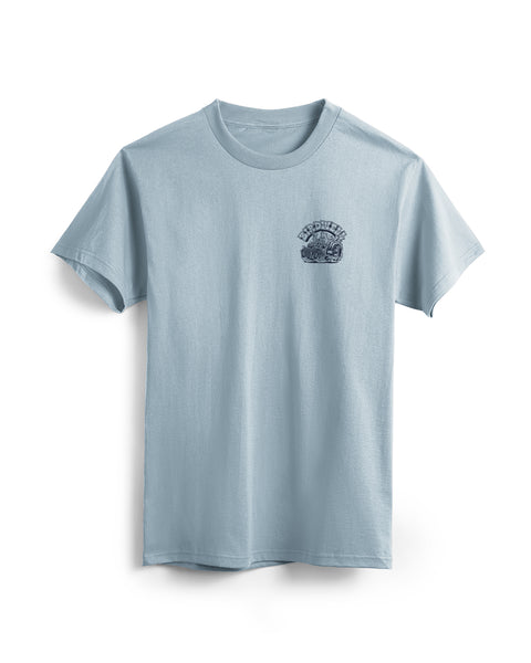 Front view of light blue t-shirt with small screen printed graphic in navy on the left chest. Screen print depicts Birdie in a vintage race car with large back wheels with smoke coming out. Birdwell is written above in an outlined Slab Serif font. 