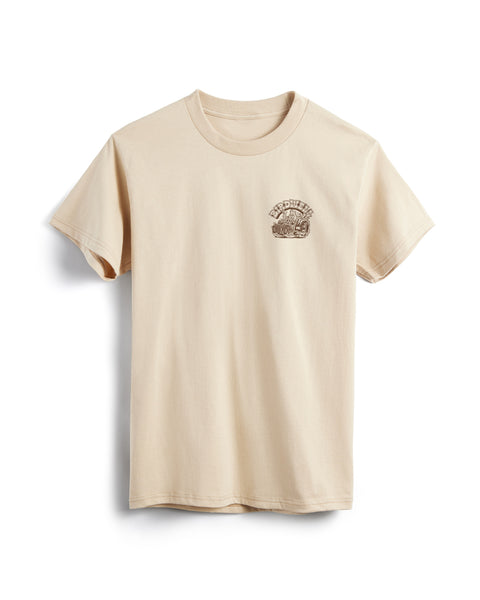 Front view of sand t-shirt with small screen printed graphic in brown on the left chest. Screen print depicts Birdie in a vintage race car with large back wheels with smoke coming out. Birdwell is written above in an outlined Slab Serif font. 