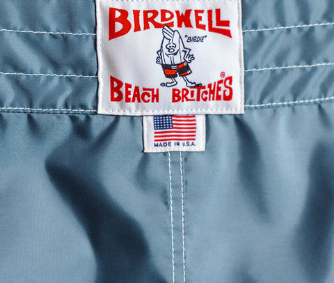 Closeup view of federal blue boardshorts and license plate label with made in usa label below it