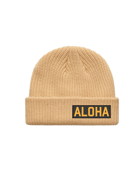 Tan Beanie with rectangular Aloha patch  with black background and yellow text. Product on white background.