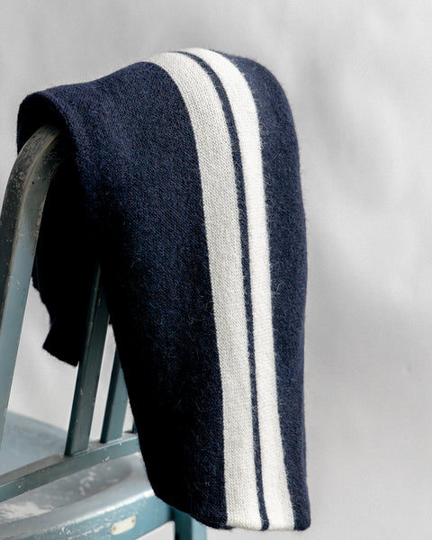 Comp Stripe Cardigan folded over the top of a greyish blue metal chair with white background.