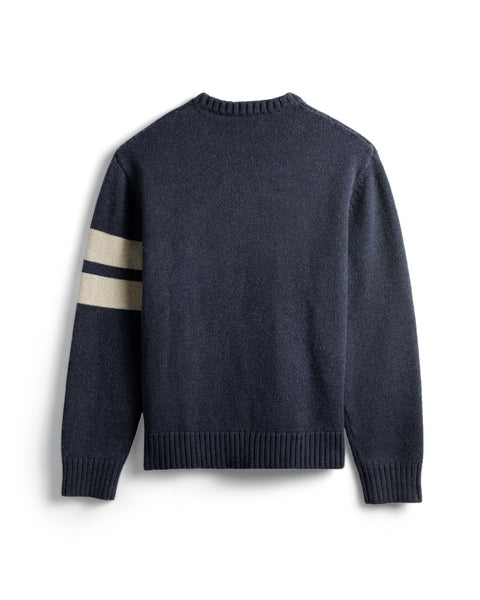 Back view of the Navy sweater with two horizontal cream stripes on the left arm. Ribbing at collar, sleeves and bottom of sweater. White background.