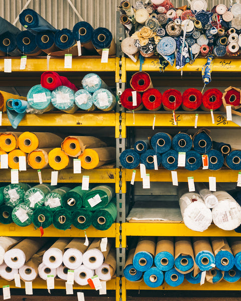 Vintage warehouse image of bolts of SurfNyl™ Fabric in navy, yellow, green, white, blue on a yellow metal shelving.