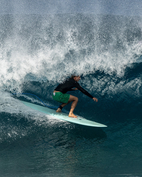 Joel wearing the 300 Boardshorts in Kelly Green while riding on a wave. Wave is curling over his head.