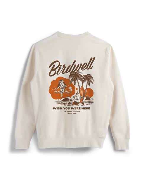 Back view of bone colored sweatshirt on white background. Screenprint on back center of the sweatshirt in brown and dark orange of Birdie leaning up against a palm tree while dreaming of a female birdie in hula skirt. 