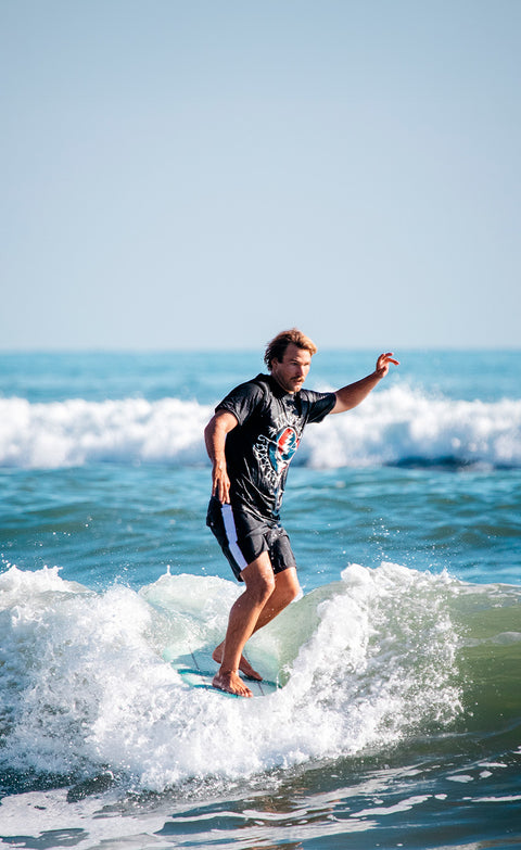 Kevin surfing with Grateful Dead x Birdwell Boardshorts & T-shirt in Black with Grateful Dead Logo.